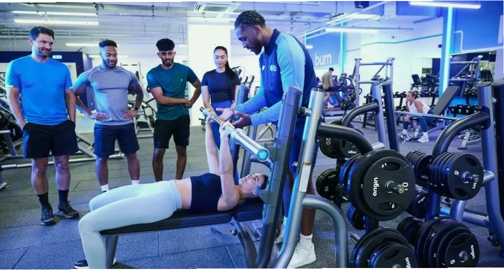 Gym trainer đang hướng dẫn người tập thực hiện bài tập với tạ
