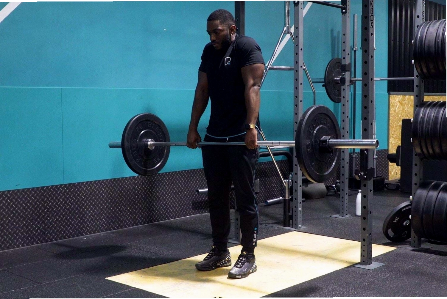Huấn luyện viên cá nhân hướng dẫn thực hiện bài tập barbell shrugs