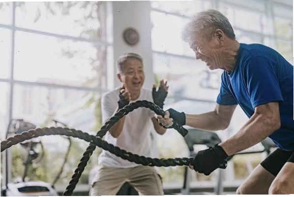 Huấn luyện viên hướng dẫn một người đàn ông tập luyện với dây thừng trong phòng gym