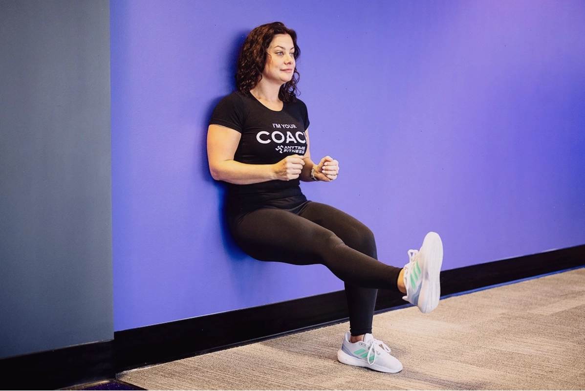 Huấn luyện viên nữ thực hiện bài tập wall sit một chân đầy thử thách