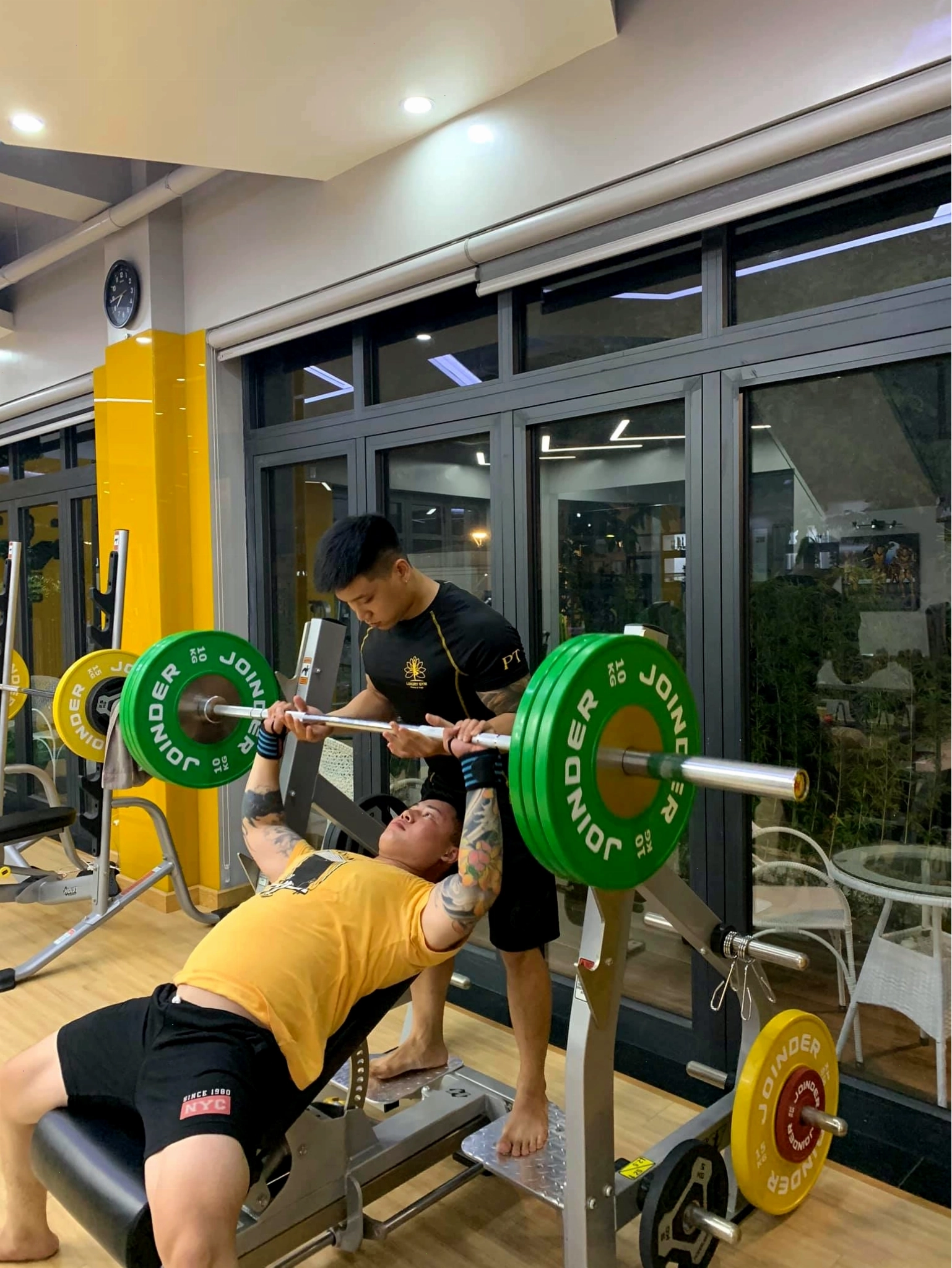 Khách hàng đẩy tạ cùng PT