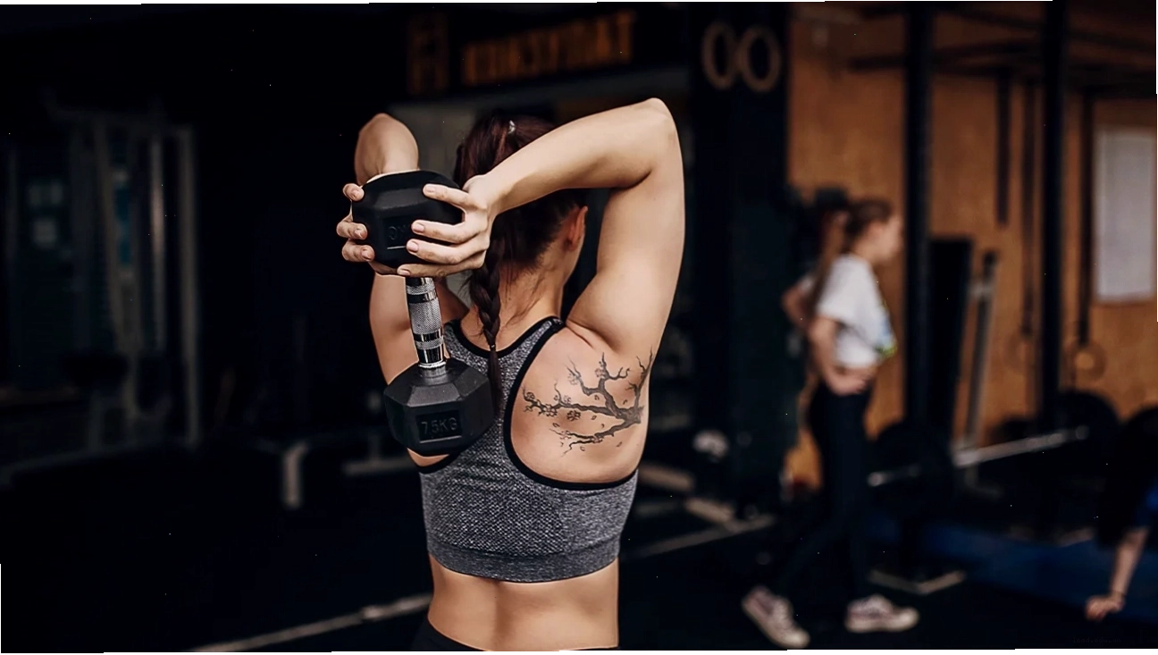Nam giới thực hiện bài tập overhead tricep extension với tạ đơn