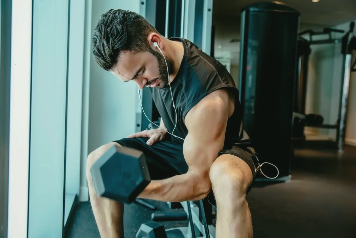 Nam vận động viên thực hiện bài tập cuốn tạ đòn (bicep curls) tại phòng gym