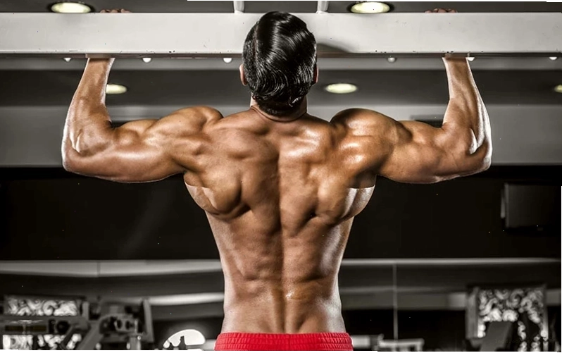 Nam vận động viên thực hiện bài tập weighted pull up với dây đai tạ
