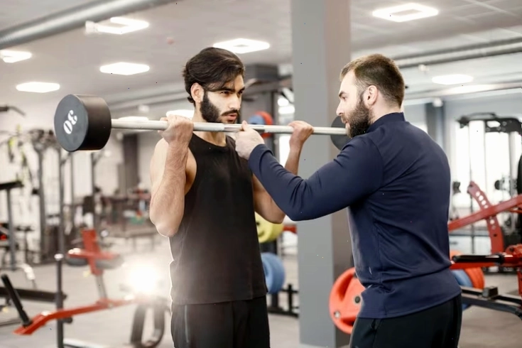 Người đàn ông Ấn Độ tập luyện trên thiết bị đặc biệt tại phòng gym với huấn luyện viên cá nhân