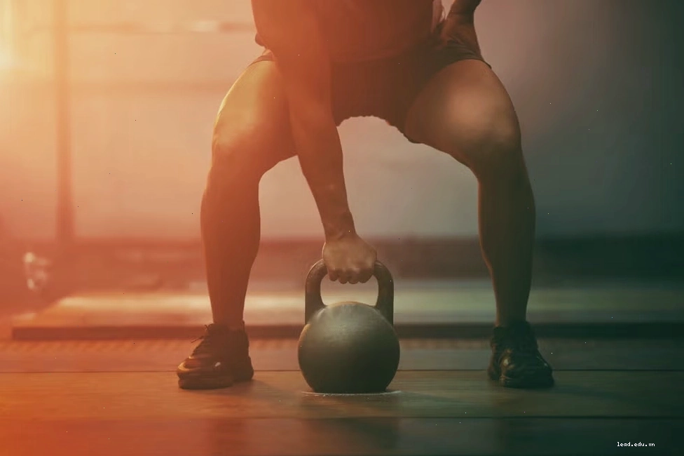 Người đàn ông tập luyện với tạ chuông trong phòng gym, nhấn mạnh sự mạnh mẽ và động lực.