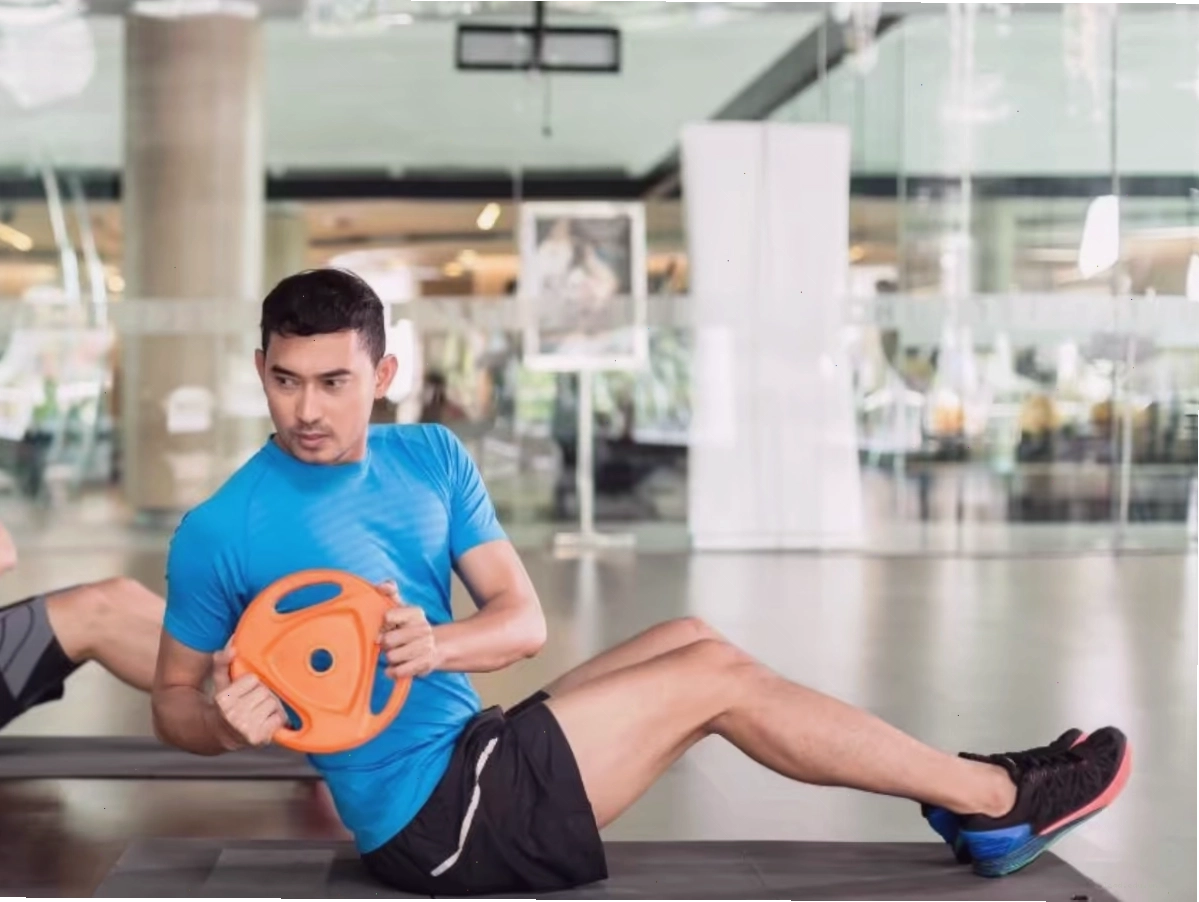Người tập đang thực hiện động tác chùng chân kết hợp xoay thân với tạ đơn