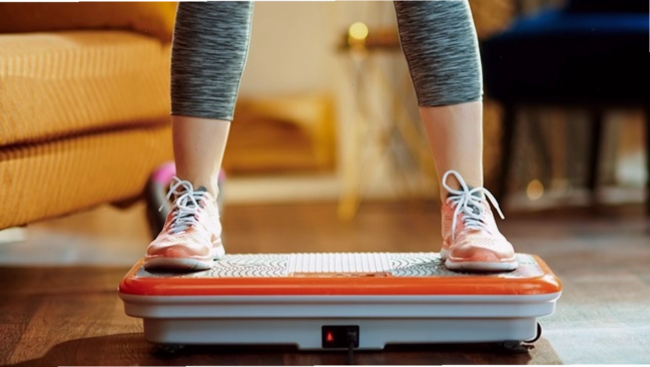 Người tập luyện trên máy rung toàn thân màu cam và xám