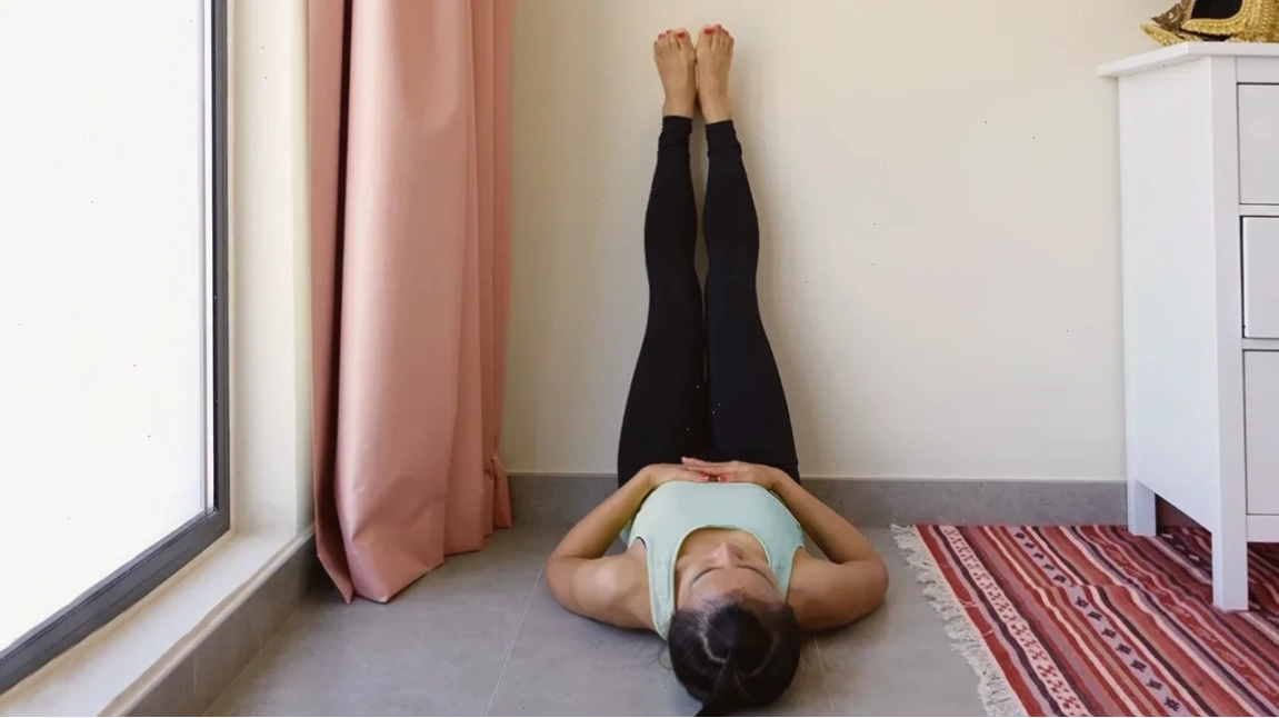 Phụ nữ thực hiện tư thế Legs Up The Wall với chân đặt trên tường