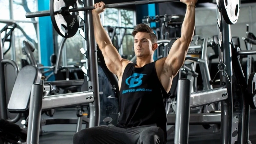 Vận động viên thực hiện bài tập đẩy tạ đôi ngồi (Seated Dumbbell Press)